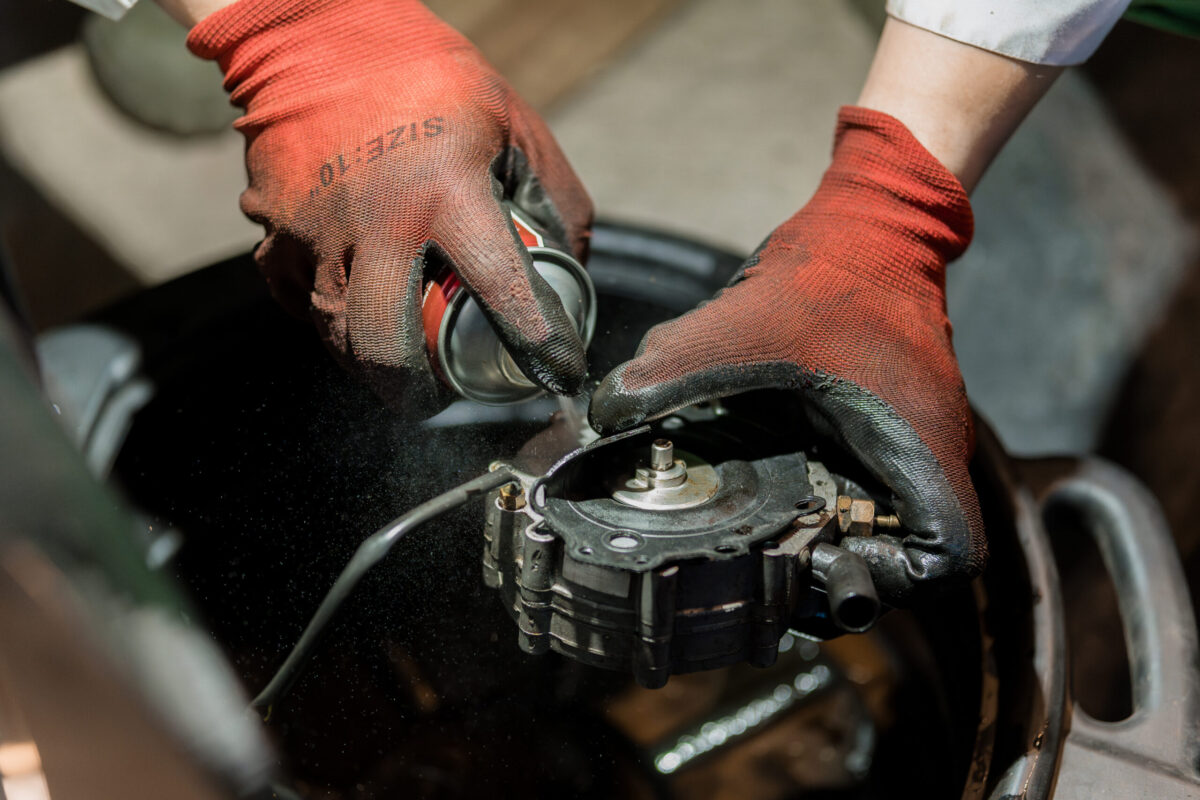 Mechanic's Hands Repairing Engine Part with Lubricant Spray